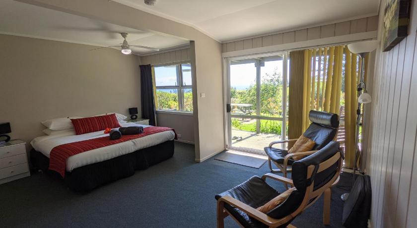 a room with a bed, chair, desk and a television, Cascade Garden Apartments in Norfolk Island