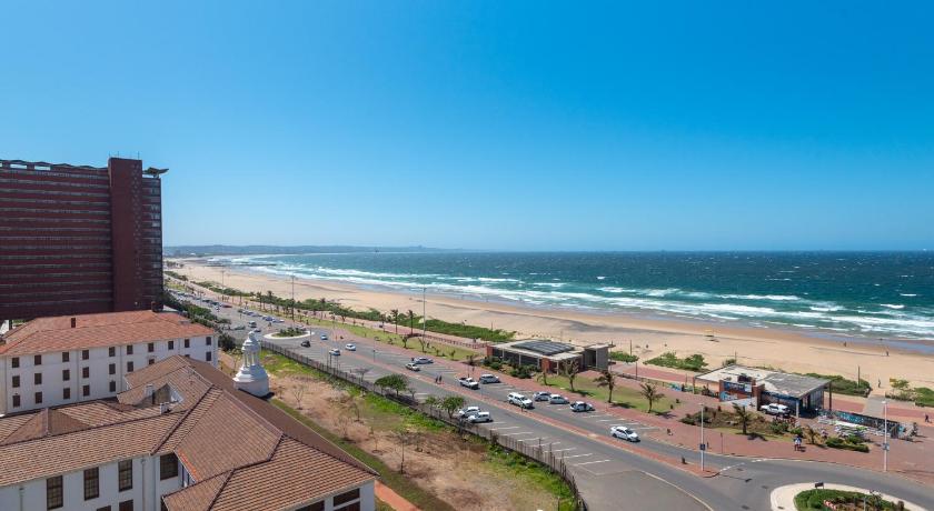 a beach scene with a large building and ocean, Lancaster Gate Apartment in Durban