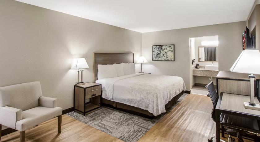 a hotel room with a bed, chair, and table, Red Roof PLUS+ Dallas - Addison in Dallas (TX)