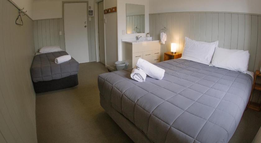 a hotel room with a bed and two lamps, Kings Ohakune Hotel in Ohakune