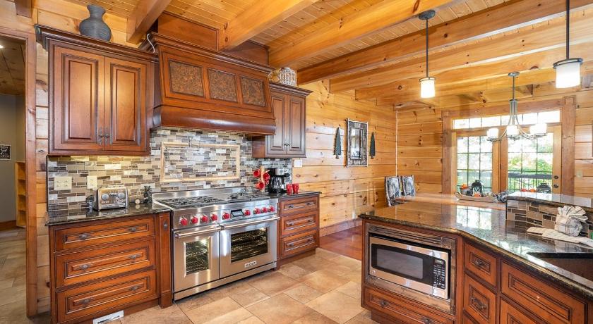a kitchen filled with wood cabinets and wooden floors, Grand Mountain Getaway Home in Pigeon Forge (TN)