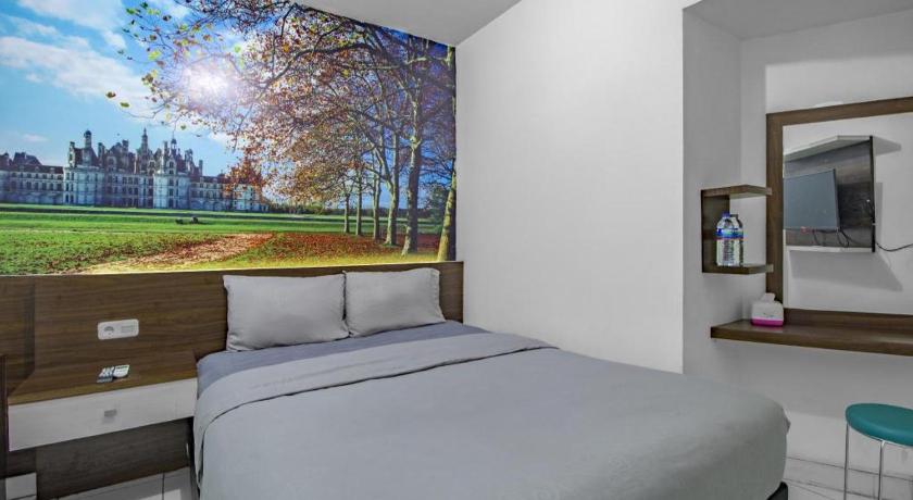 a bedroom with a painting on the wall, Green Stay Inn in Jakarta