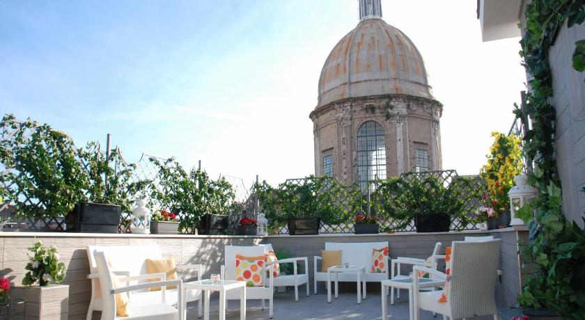 a large building with a patio with tables and chairs, Hotel San Pietro in Naples