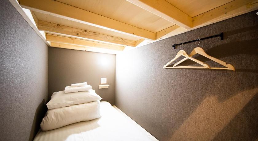 a bedroom with a bed and a mirror, Ten to Ten Hostel in Sapporo