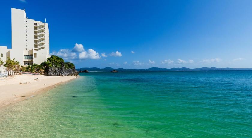 a beach with a blue sky and palm trees, Hotel Resonex Nago in Okinawa Main island