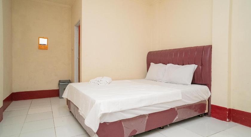 a bed in a room with a white bedspread, Arwana Homestay Syariah in Jakarta