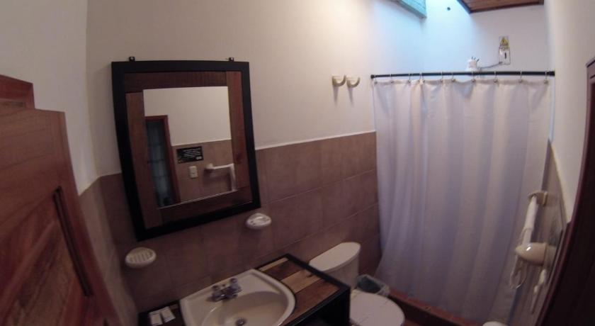 a bathroom with a sink, toilet and mirror, Jardin Cafe Hotel & Restaurant in Gracias