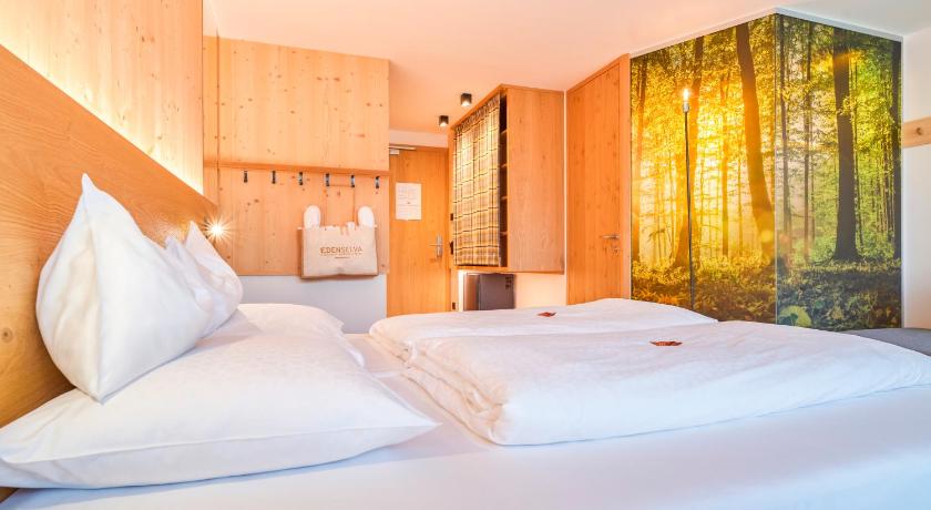 a bedroom with a white bed and white walls, Mountain Design Hotel Eden Selva in Selva di Val Gardena