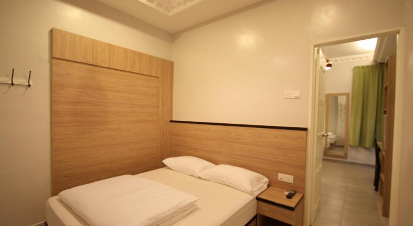a hotel room with a bed and a dresser, Shamrock Guest House in Ipoh