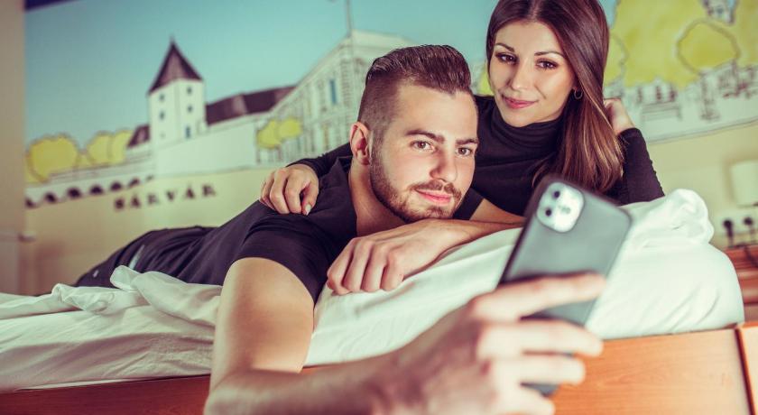 a man and a woman are looking at a cell phone, Hotel Viktoria in Sarvar