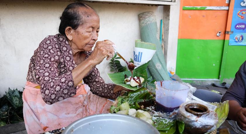 a woman sitting at a table with a bowl of vegetables, Khas Tugu (formerly Pesonna Hotel Tugu Yogyakarta) in Yogyakarta