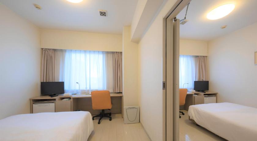 a hotel room with two beds and a television, Smile Hotel Okinawa Naha in Okinawa Main island