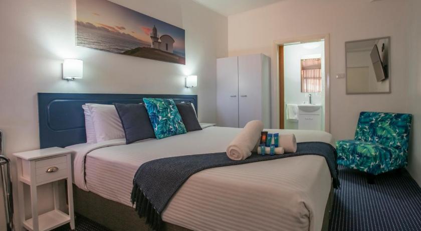 a hotel room with two beds and a television, Ocean Breeze Motel in Port Macquarie