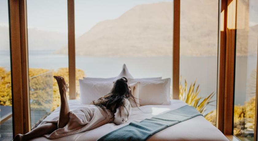 a woman laying on a bed in front of a window, Azur Lodge in Queenstown