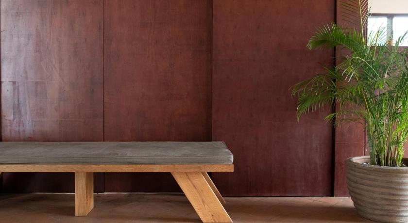 a wooden bench sitting in front of a green plant, Le Sen Boutique Hotel in Luang Prabang
