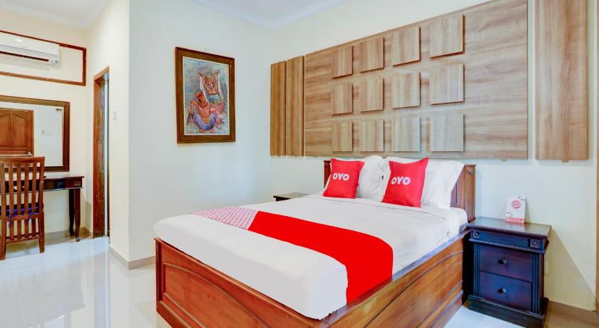a bedroom with a bed, a desk and a painting on the wall, OYO 1762 Hotel Astiti Graha Tanah Lot in Bali