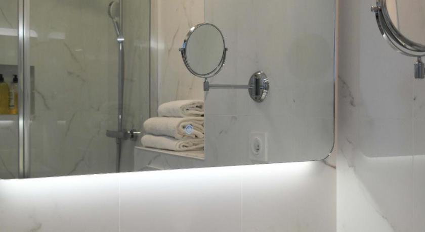 a white sink sitting under a mirror in a bathroom, Hotel Belle Vue Marseille in Marseille