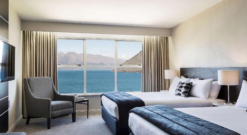 a hotel room with a bed and a chair, Mercure Queenstown Resort in Queenstown