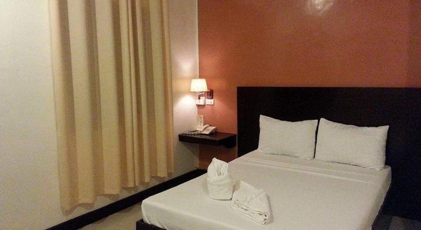 a hotel room with a bed and two lamps, Dolyn Suites in General Santos City