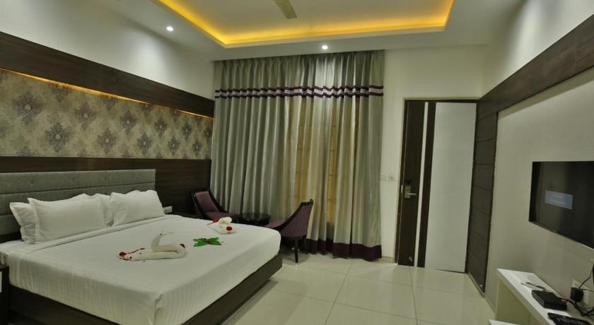 a hotel room with a large bed and a large window, Jhansi Hotel in Jhansi