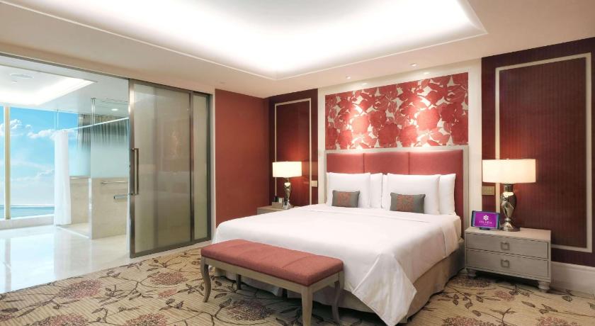 a hotel room with a bed and a dresser, Okada Manila in Manila