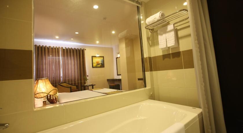 a white bath tub sitting next to a white sink, Lac Long Hotel Hai Phong in Haiphong