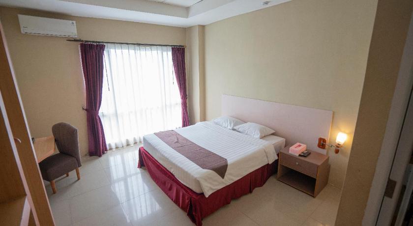a hotel room with a bed, chair, and nightstand, Bangka City Hotel in Bangka