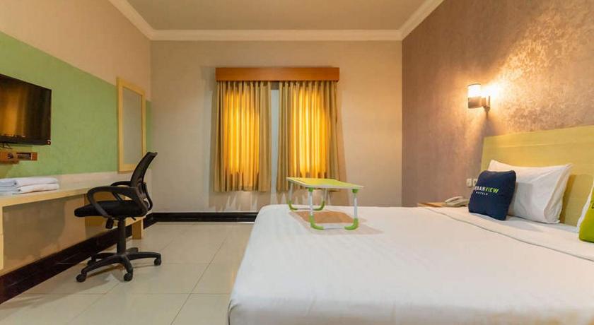 a hotel room with a bed, chair, and table, Urbanview Hotel Raja Jambi in Jambi