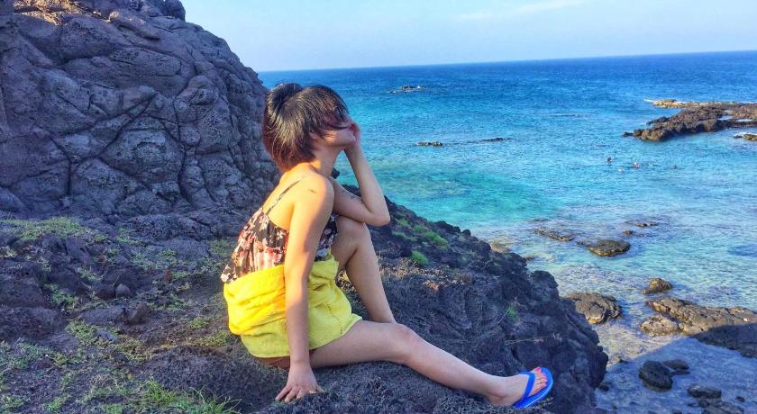a woman sitting on a rock looking at the ocean, Villa Đai Duong 2 View bien in Huyen Phu Quy