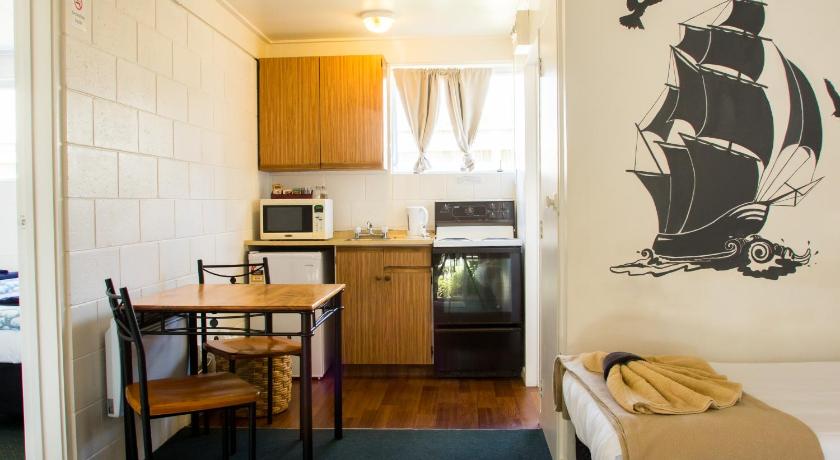 a kitchen with a table and a refrigerator, Alpha Motor Inn in Palmerston North