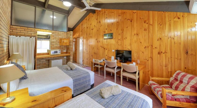 a bedroom with a bed, chair and a tv, All Travellers Motor Inn in Coonabarabran