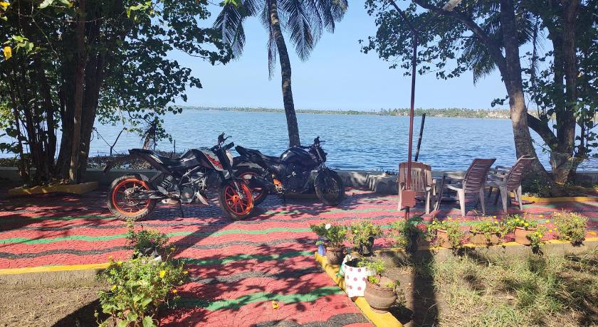 motorcycles are parked on the grass near the water, West Wind Homez - Home Stay in Kochi
