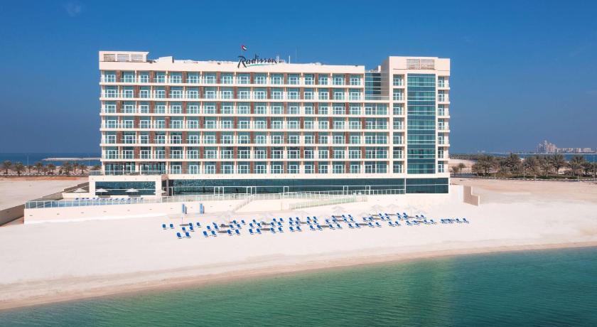 a large white beach with a large blue and white building, Radisson Resort Ras Al Khaimah Marjan Island in Ras Al Khaimah