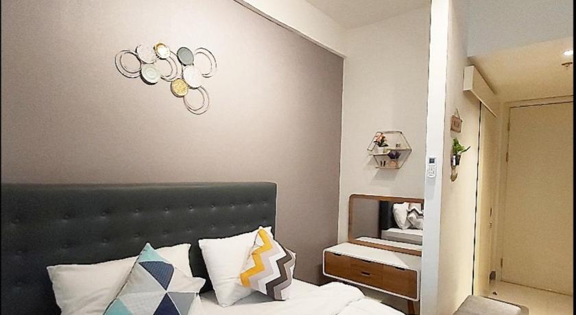 a bedroom with a bed, a dresser and a lamp, Apartemen Amor Pakuwon City  in Surabaya