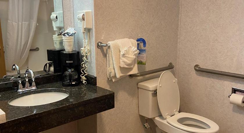 a bathroom with a toilet a sink and a mirror, Days Inn & Suites by Wyndham Williston in Williston (ND)