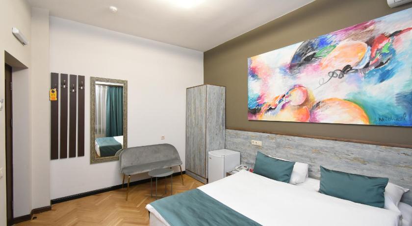 a hotel room with a bed, tv, and paintings on the wall, Yerevan Boutique Hotel in Yerevan