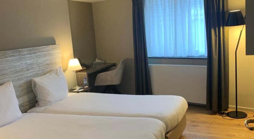 a hotel room with a bed and two lamps, Hotel Au Quartier in Maastricht