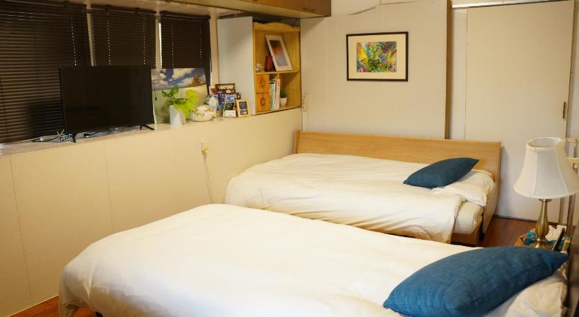 a hotel room with two beds and a television, Guest House Renga II in Okinawa Main island
