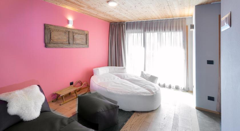 a room with a bed, a chair, and a window, Aux Pieds du Roi - Suite & Spa in Valtournenche