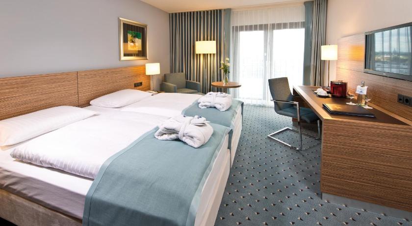 a hotel room with two beds and a television, Maritim Hotel Darmstadt in Darmstadt