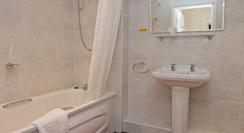 a white bath tub sitting next to a white sink, The Winter Dene in Bournemouth