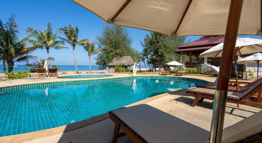a patio area with a pool, chairs, and an umbrella, Gooddays Lanta Beach Resort SHA in Koh Lanta