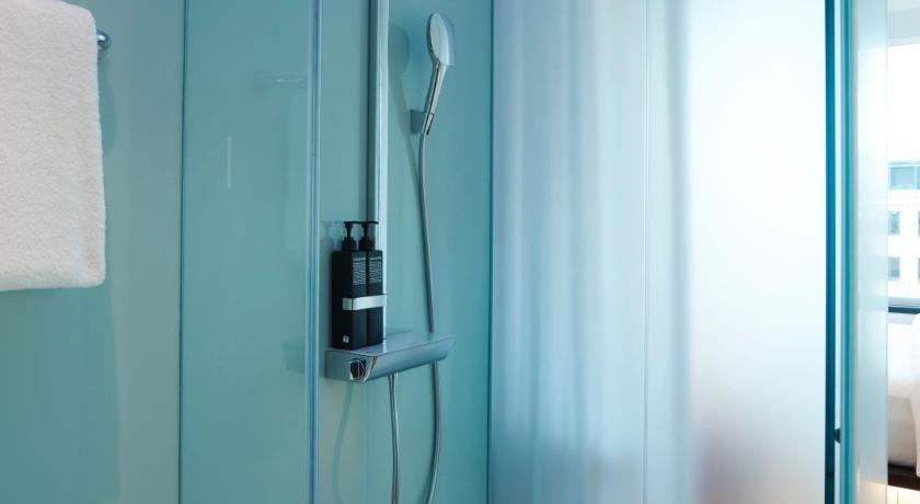 a bathroom with a shower curtain and a glass door, citizenM Tower of London in London