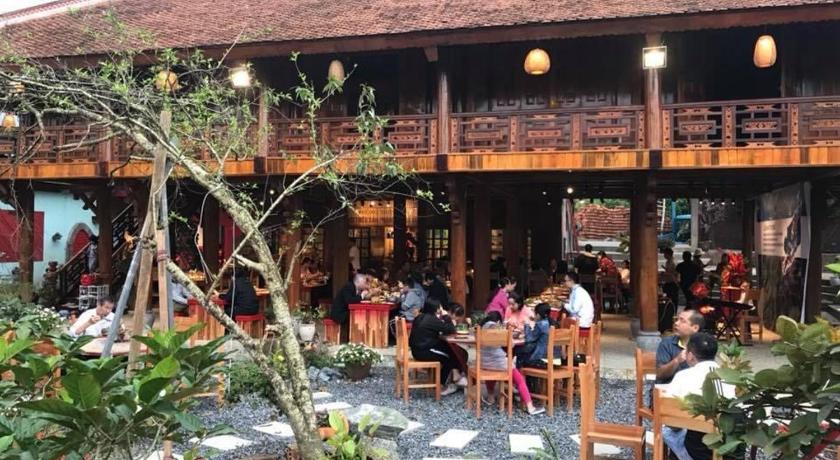 people sitting at tables outside of a building, Maison Teahouse homestay in Ha Giang