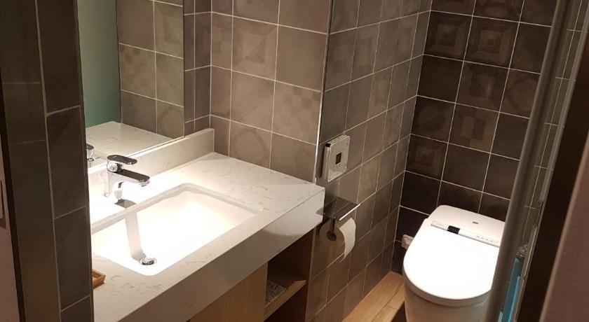 a bathroom with a toilet, sink, and mirror, Bentley Hotel in Taoyuan