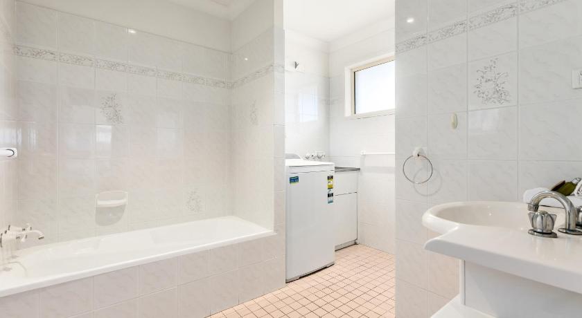 a white bath tub sitting next to a white sink, Hungerford Beach Apartment by Kingscliff Accommodation in Kingscliff