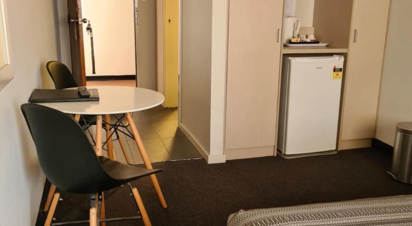 a kitchen with a table and chairs and a refrigerator, Belconnen Way Hotel & Serviced Apartments in Canberra