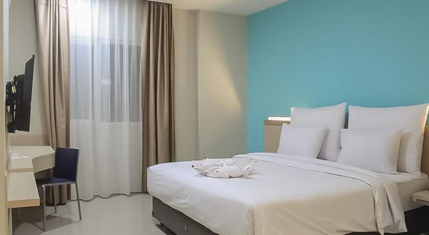 a hotel room with a bed and a dresser, Hotel Mutiara RedPartner in Padang Sidempuan