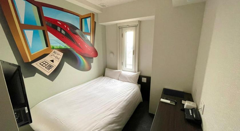 a room with a bed, a desk and a painting on the wall, TOKYO CITY VIEW HOTEL TABATA-STATION in Tokyo