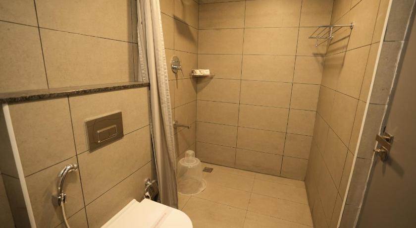 a bathroom with a toilet and a shower stall, GRAND GANPAT in Vellore